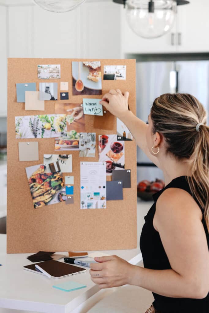 photographer planning out the clients mood board and photoshoot on a cork board