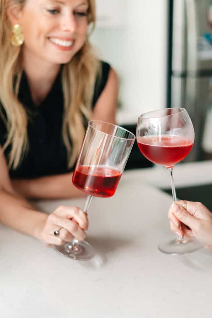 two women cheers red cold wine in wine glasses for branding photography shoot