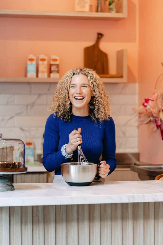 Baker with blonde curly hair mixed dough in a bowl for a branding photography shoot